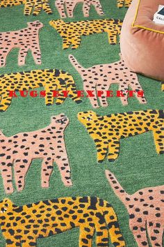 a green rug with giraffes and zebras on it in front of a pillow