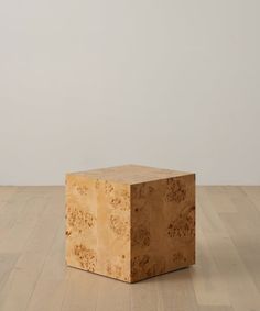 a wooden block sitting on top of a hard wood floor next to a white wall