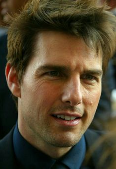 a close up of a person wearing a suit and tie with hair in the wind