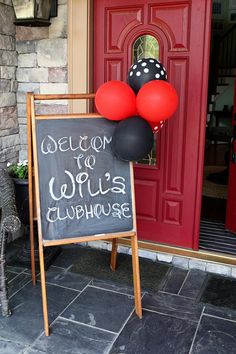 a welcome sign with red and black balloons in front of a door that says welcome to willis's clubhouse