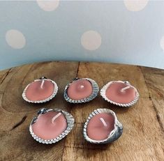 four pink candles sitting on top of a wooden table