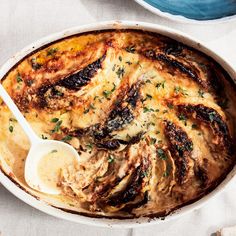 a casserole dish with meat and cheese in it on a white tablecloth