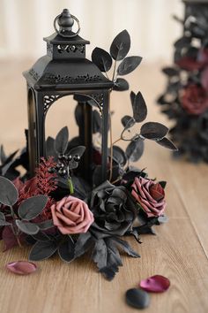 an old fashioned lantern with flowers and leaves on the floor in front of two other lanterns