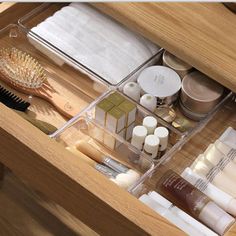 an open drawer with cosmetics and other items in it on top of a wooden table