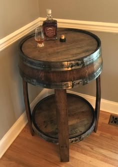 a wooden table with a bottle on top of it next to a wall and hardwood floor