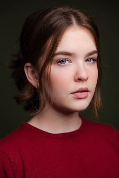 a young woman with blue eyes is posing for a photo in front of a dark background