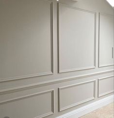 an empty room with white paneling and beige walls