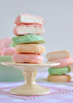 a stack of colorful cookies sitting on top of a cake plate next to other desserts