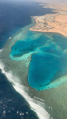 an aerial view of some very pretty blue water in the middle of the ocean and land