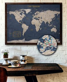 a world map hanging on the wall next to a wooden table with coffee mugs