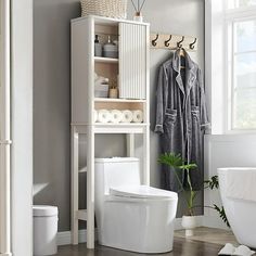 a white toilet sitting next to a bath tub in a bathroom on top of a hard wood floor