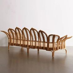 a wooden bench made out of wicker on top of a hard wood floor next to a white wall