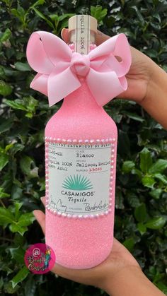 a hand holding a pink bottle with a pink bow on it's top that says cascarinoos tequila