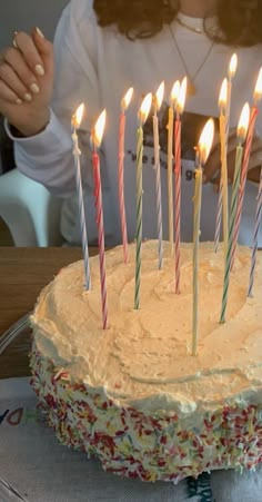 a woman sitting in front of a cake with lit candles