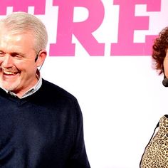 two people standing next to each other in front of a pink sign with the words free on it