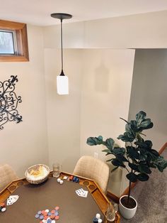 a dining room table with chairs and a potted plant in the corner next to it