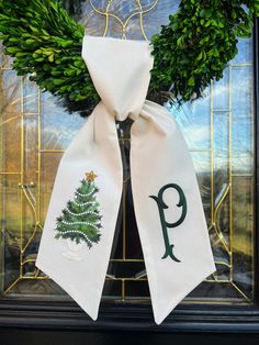 a christmas wreath with a monogrammed tree and letter p on it, hanging in front of a glass door