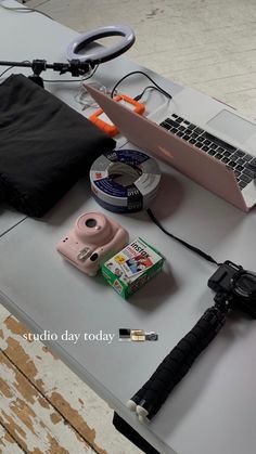 an open laptop computer sitting on top of a table next to a camera and other items