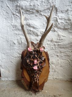 a deer's head with antlers and flowers on top of a piece of wood