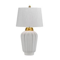 a white lamp with a gold base and shade on it's side, against a white background