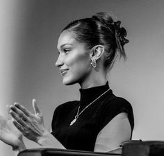 a black and white photo of a woman sitting in a chair with her hands together