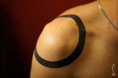 the back of a woman's shoulder with a circle tattoo on her left arm