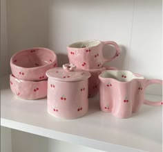 pink ceramic dishes and cups are sitting on a shelf