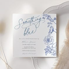 a white and blue wedding card on top of a table