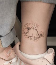 a small tattoo on the ankle of a person with a pink sneaker and rose