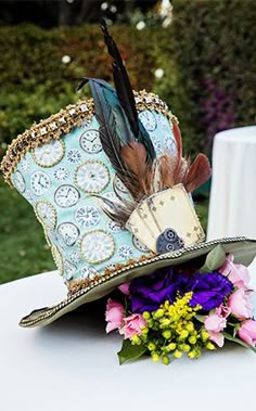 a fancy hat with feathers and flowers on a table