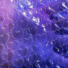 many hearts are placed in the middle of purple and blue material, as if they were made out of plastic