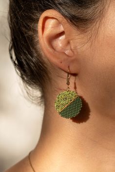 a close up of a person wearing earrings and a necklace with an ornament on it