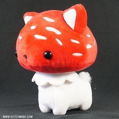 a red and white stuffed animal on a black background