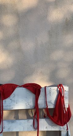 a red umbrella sitting on top of a white bench next to a wall and tree