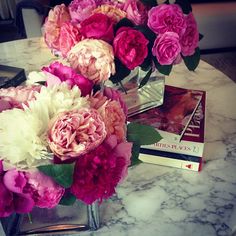 pink and white flowers sitting on top of a marble table