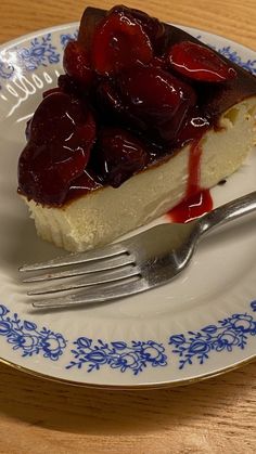 a piece of cheesecake with cherries on top is sitting on a blue and white plate