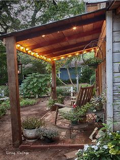 an outdoor covered patio with chairs and potted plants on the side of the house