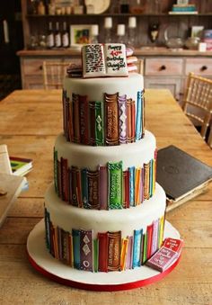 a three tiered cake with books on it sitting on top of a wooden table