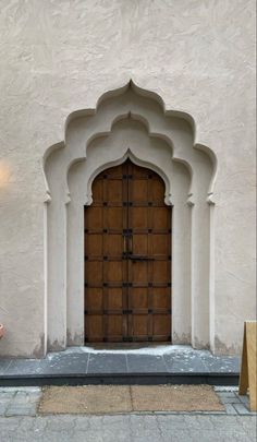 a woman sitting on a bench in front of a building with an arched doorway and wooden door