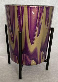 a purple and gold vase sitting on top of a metal stand