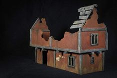 a toy house made out of clay on a black background with the roof ripped off