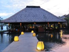 some lights that are sitting on the side of a water way in front of a gazebo