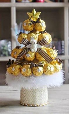 a small christmas tree made out of chocolates and gold foil wrapped in white feathers