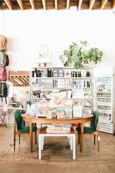 a table and chairs in a room with shelves full of items on the wall behind it