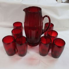 a group of red glass cups sitting next to each other on a white tablecloth