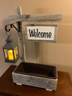 a welcome sign on a wooden frame next to a lantern