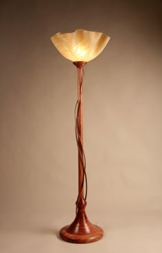 a wooden floor lamp with a glass shade on it's top and an iron base