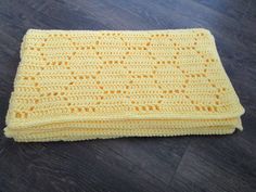 a yellow crocheted blanket laying on top of a wooden floor