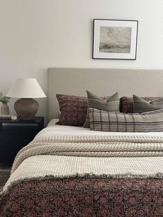 a bedroom with a bed, night stand and two lamps on either side of the bed