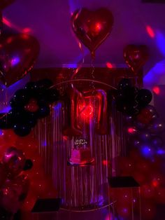 some balloons are floating in the air and heart shaped balloons hanging from the ceiling above them